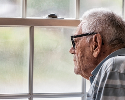 elderly man looking out of a window