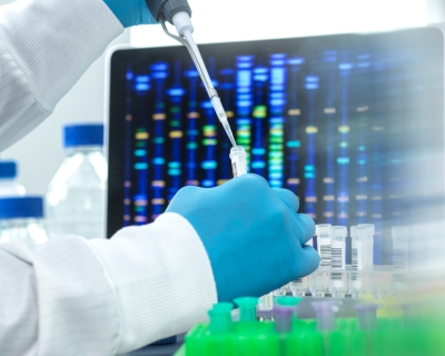 A scientist pipetting a sample into a vial for DNA testing.